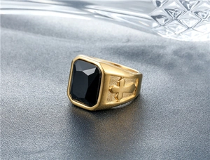 Macro shot of men's gold plated ring with black rectangle gem and cross relief