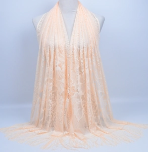 Detailed view of peach crochet lace shawl with floral cutouts and fine fringe tassels