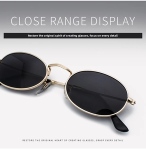 Close-up of retro oval sunglasses with a polished gold metal frame and dark lenses