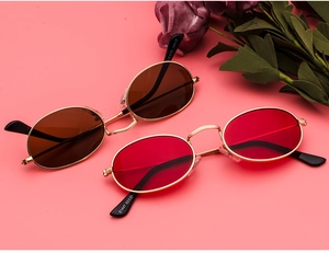 Detail of oval vintage metal sunglasses in red and brown lenses on a pink background