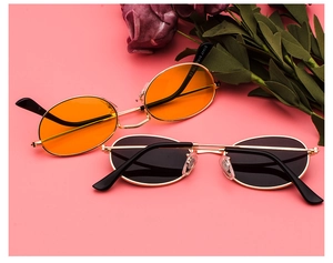 Macro detail of oval metal sunglasses with orange and black lenses on vintage background