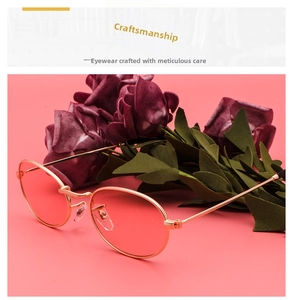 Detailed view of oval pink lens sunglasses with slim gold metal frames on pink backdrop