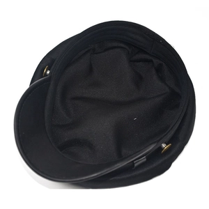 Detailed top view of a black navy flat top cap featuring golden side buttons and clean stitching