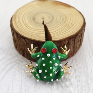 Detailed macro view of the green enamel frog brooch featuring white pearls and red rhinestone eyes