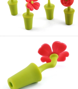 Macro detail of red flower-shaped silicone wine bottle stopper with green leaf stem base