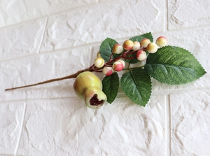 Macro shot of artificial berry branch with red-yellow gradient berries and green leaves