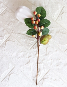 Detailed view of red and yellow artificial berries with green leaves on textured brown stem