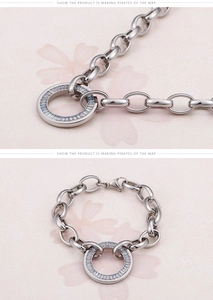 Detail of silver chain bracelet featuring a round pendant with baguette-cut stones