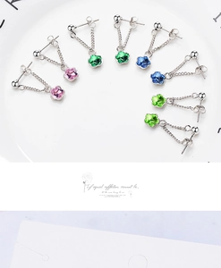 Macro detail of four pairs of floral crystal stud earrings with silver chain drops