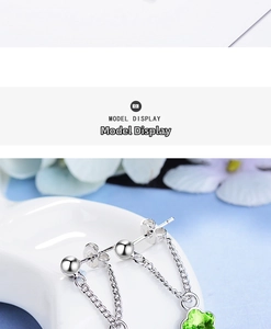 Detail of silver drop earrings with green clover crystal and delicate chain design