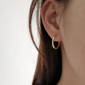 Polished 925 sterling silver golden irregular hoop earring worn on female model ear