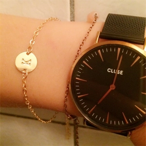 Rose gold letter K bracelet and Cluse watch worn together on a wrist in a daily style
