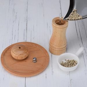 Manual wooden pepper mill set with ceramic core and wooden base on white surface