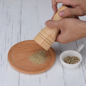 Manual wooden pepper grinder with ceramic core on a white vintage tabletop setting