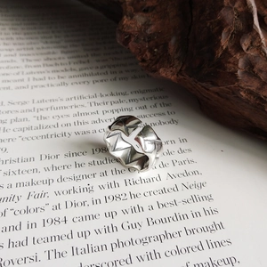 Close-up of a 925 sterling silver ring with geometric textured pattern on a vintage book