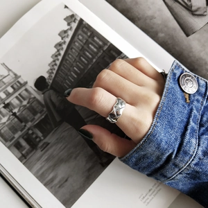Close-up of a silver 925 woven ring with irregular textured metal on a model's finger