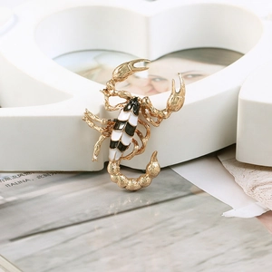 Macro detail of a golden scorpion brooch with black and white enamel finish