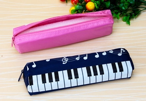 Pink and navy piano note canvas pencil pouches for students on a striped desk background