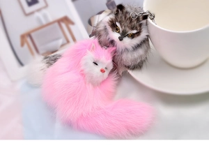 Close-up of plush fox keychains in pink and taupe with fluffy fur and metal clips