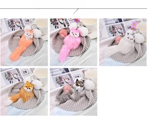 Detail showing five colors of plush fox keychains on a cozy lifestyle background