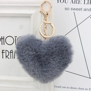 Close-up of a soft grey heart-shaped faux fur pom pom keychain with gold metal clip