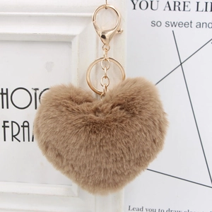 Detailed macro view of heart-shaped faux fur keychain in khaki with gold metal hardware