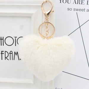 Close-up of a heart-shaped off-white plush keychain with a gold ring on a white frame