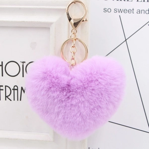Close-up of a light purple plush heart keychain with a gold-tone metal clasp on a desk