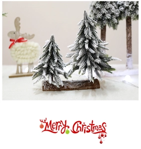 Close-up of mini snowy Christmas trees on a rustic wooden base for table decoration