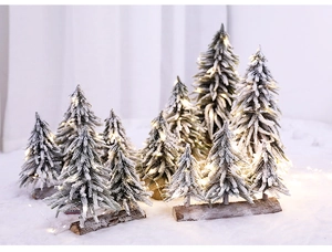 Detail of mini flocked Christmas trees with warm LED lights and rustic wooden base