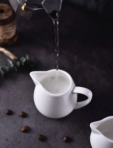 Detailed view of white ceramic cream pitcher showing smooth glaze and ergonomic handle