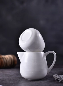 Detail showing white ceramic sauce pitcher with textured ridges and non-slip matte base