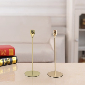 Close-up of dual gold metal candlesticks for wedding decor on a beige tabletop surface