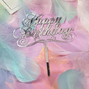 Macro shot of silver mirror acrylic Happy Birthday cake topper on soft feather background