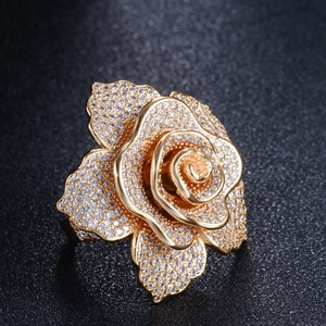 Macro shot of rose-shaped gold ring with cubic zirconia petals on black surface
