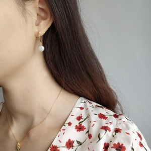Close-up of golden heart necklace and pearl hoop earrings worn by a female model