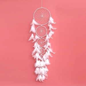 Close-up of white multi-ring dreamcatcher with feathers against a pink background