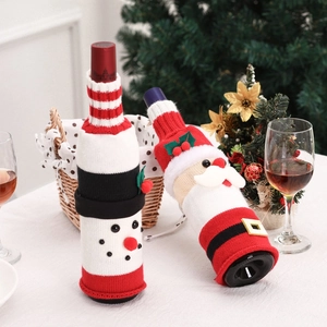 Close-up of knitted Santa and Snowman wine bottle covers on a festive Christmas dining table