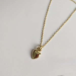 Polished golden heart pendant necklace with leaf detail on vintage magazine background