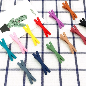 Macro detail of multi-colored matte hair clips with minimalist cross design on grid fabric