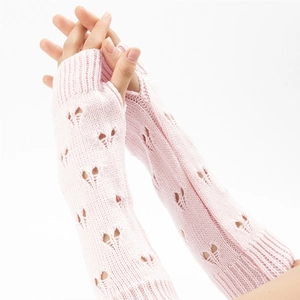 Detail of pink knitted fingerless arm warmers with heart-shaped cutouts for women