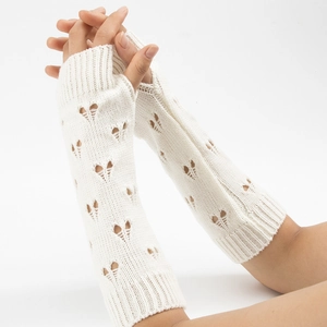 Detailed close-up of cream knit arm warmers featuring heart-shaped cutout pattern