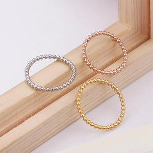 Minimalist beaded stackable rings in silver, gold, and rose gold finish on wood display