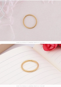 Vue détaillée d'une bague en perles dorées en acier titane sur fond minimaliste
