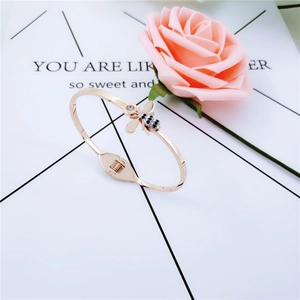 Détail d'un bracelet abeille en or rose orné de cristaux noirs et blancs sur fond rose