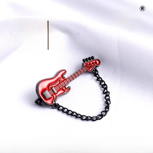 Detailed macro of a vintage red guitar brooch with black metal chain on white fabric