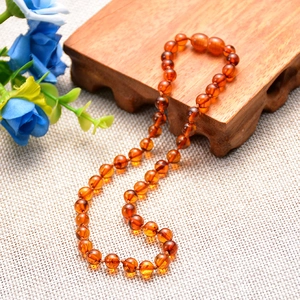 Handcrafted Baltic amber beaded necklace for babies featuring polished round orange beads