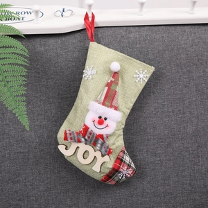 Détail d'une chaussette de Noël en lin vert avec bonhomme de neige 3D et décor JOY en bois