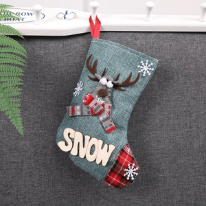 Détail de chaussette de Noël en toile de jute verte avec renne 3D et patch en bois SNOW