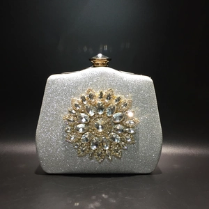 Close-up of sparkling silver glitter evening clutch with large rhinestone flower ornament